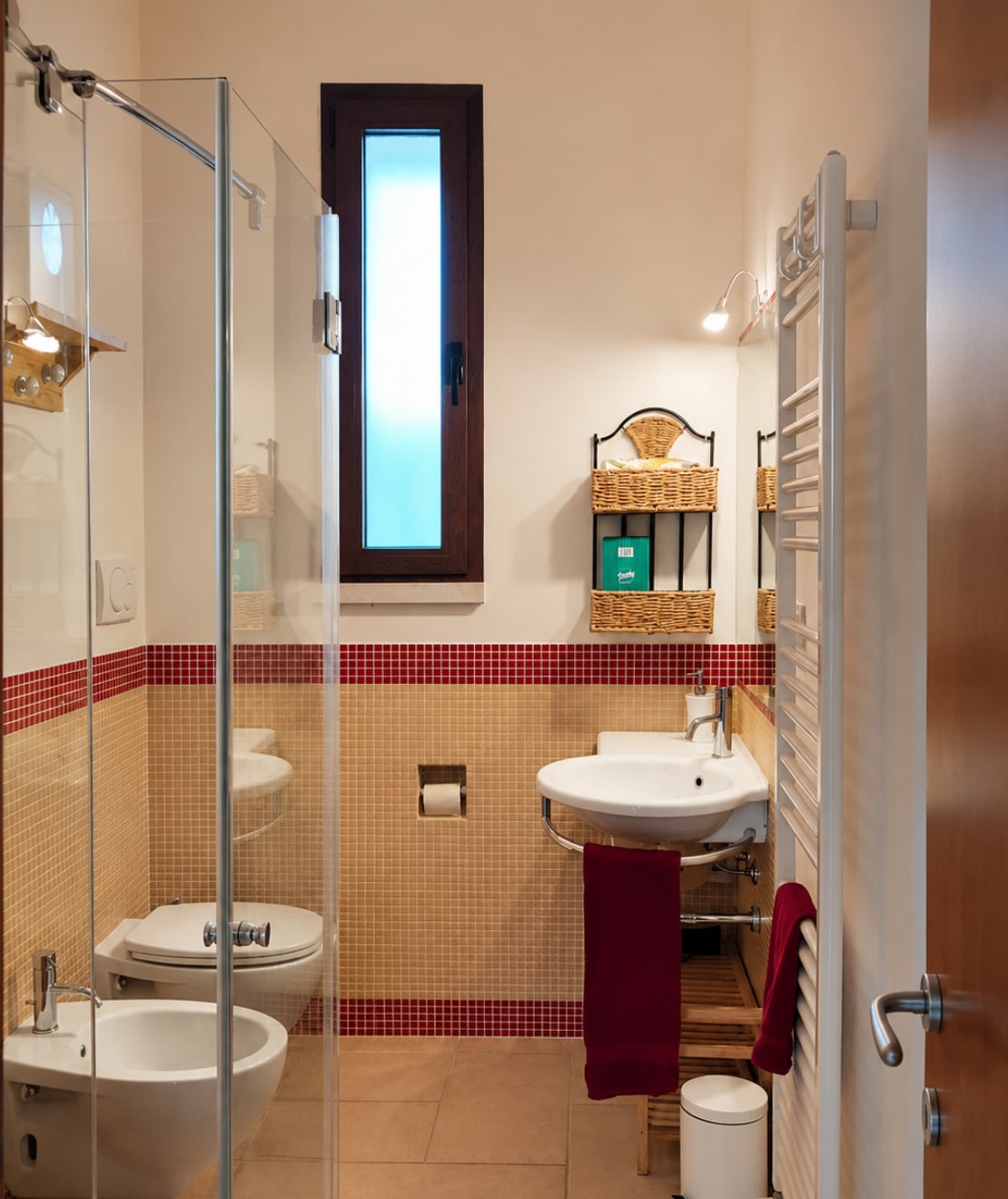 Bagno moderno di Villetta Gelsomino con doccia in vetro, lavabo sospeso e finestra verticale.
