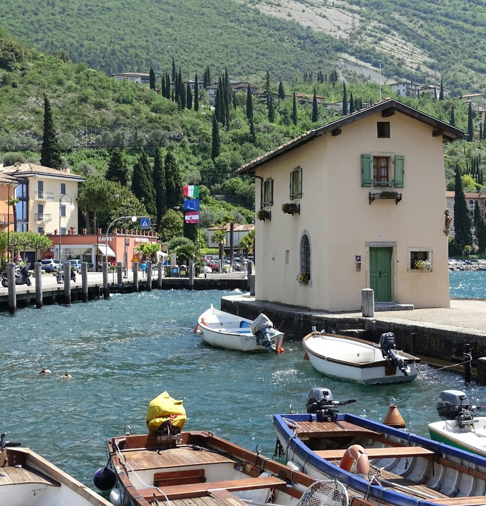 Piccolo porticciolo sul Lago di Garda con barche e case colorate.